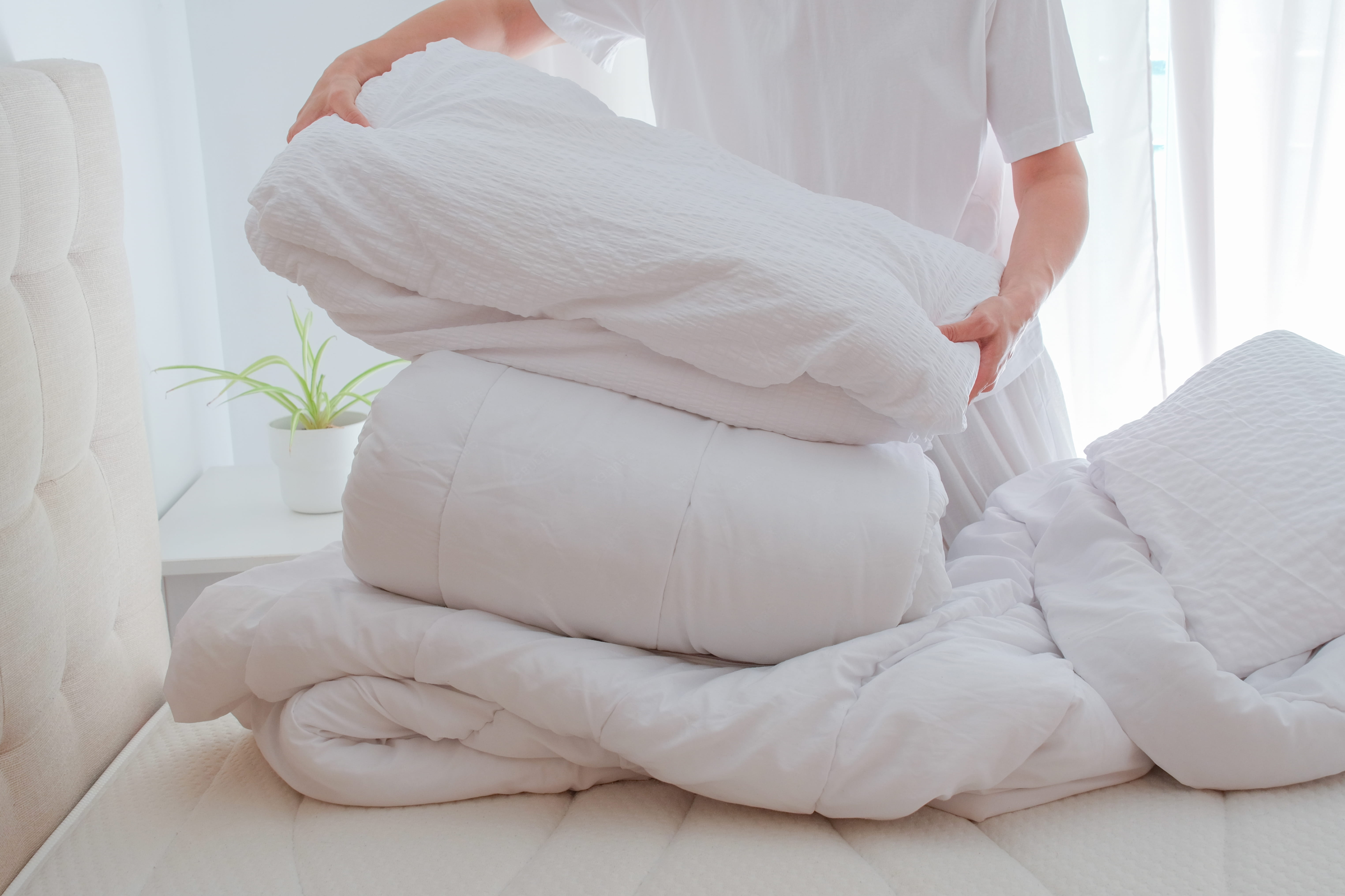 Vacation rental turnover cleaning. Cleaner changing bed linens.