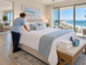 Cleaner making a bed in a bright beachfront vacation condo overlooking the ocean